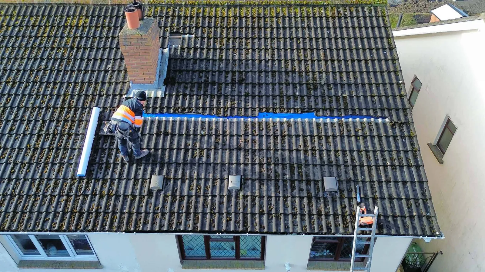 Roofer re-tiling a repaired section of roof