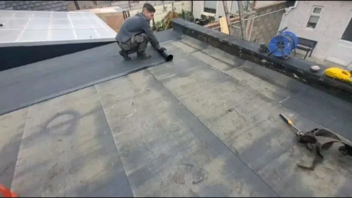 Roofer laying felt on a flat roof